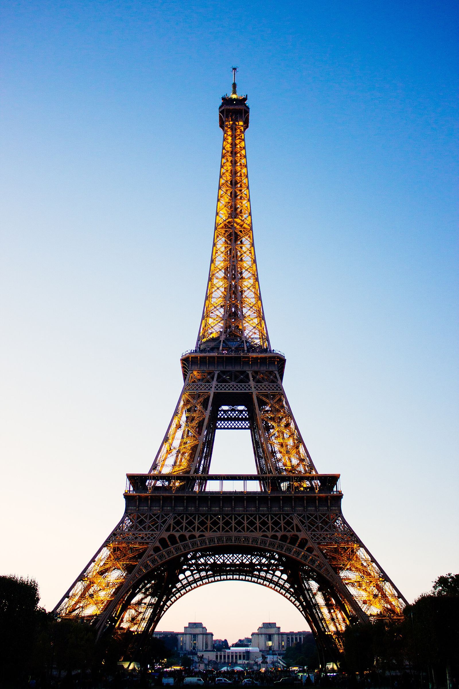 The Eiffel Tower at dusk, seen through trees.